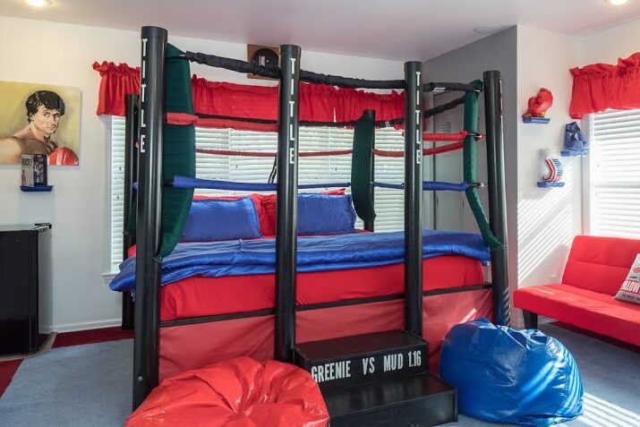 an image of a boxing ring bed with blue and black accent, bean bag, boxing gloves on wall, and boxing poster on wall