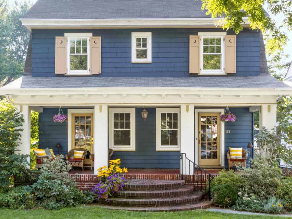 a front view of a grey exterior house with wooden cedar shutters on windows and door