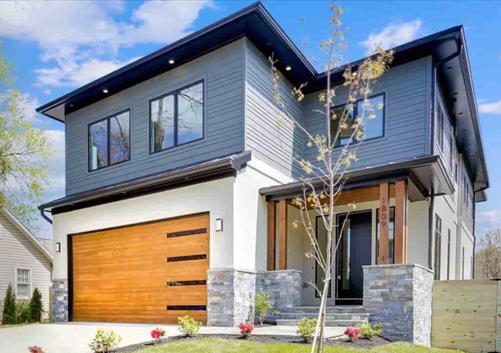 a full view of grey house with cedar garage door