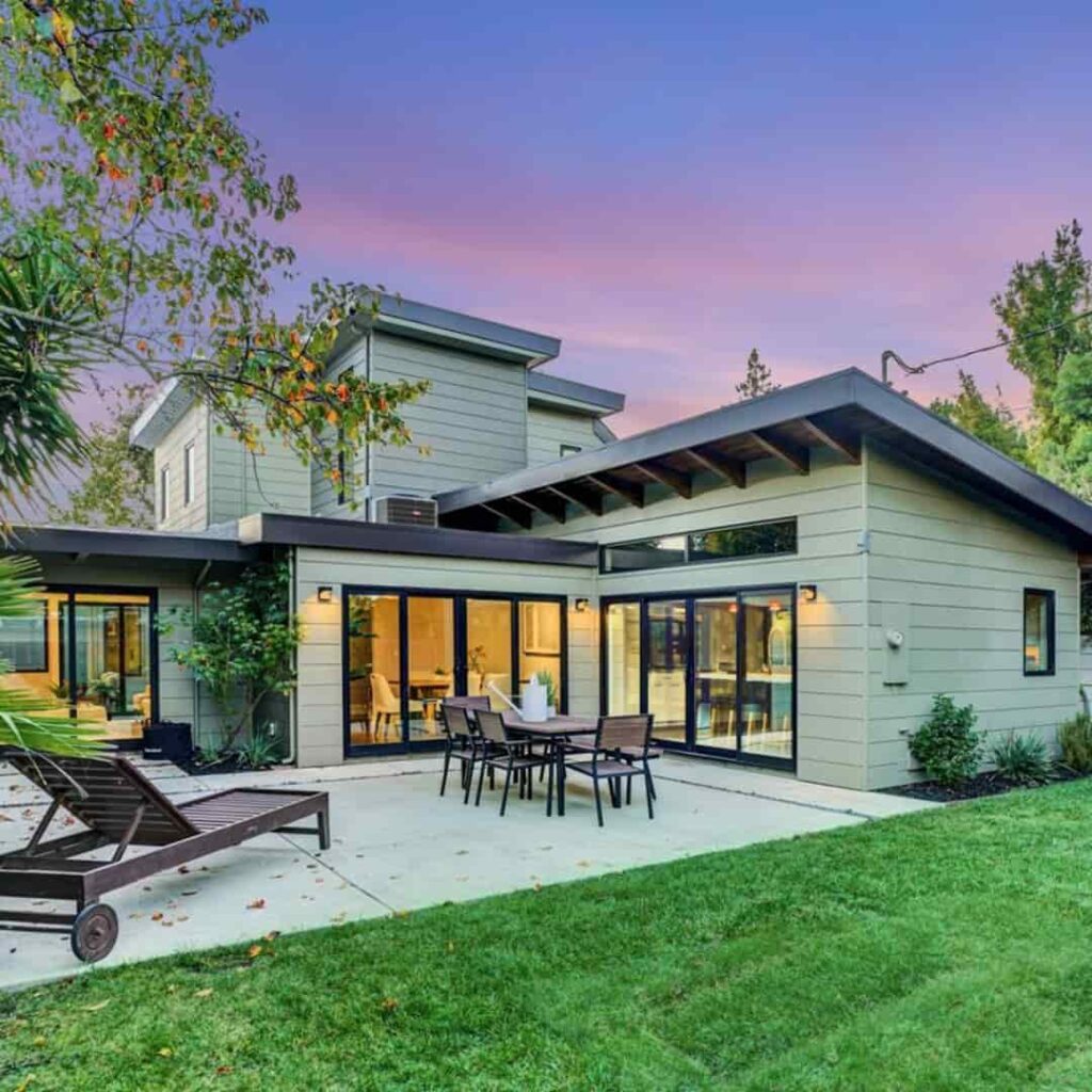 an image of a modern style sage green bungalow with black trim on roofline and window trims