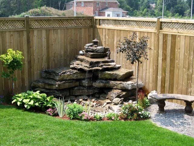 an image of small rock corner garden with slabbed rocks, plants, and some pebbles