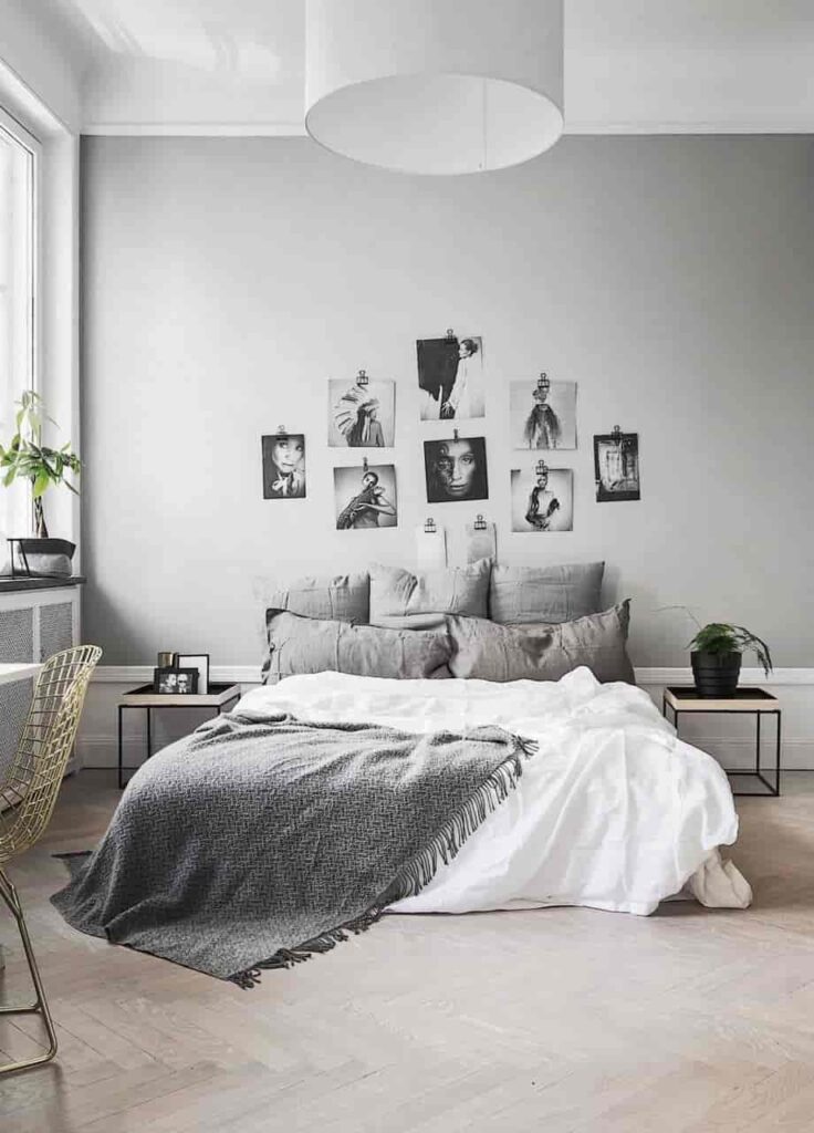 a minimalist budget friendly bedroom with a grey wall and pillows, simple sophisticated 