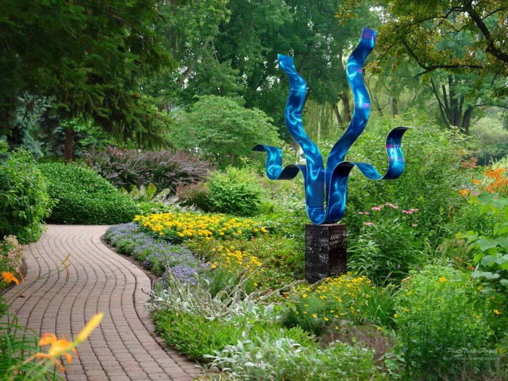 an image of a blue metallic shiny sculpture in a farytale garden for an english cottage