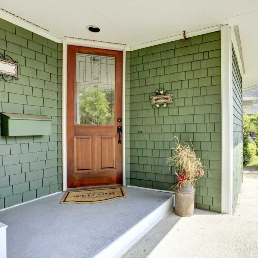 an image of a sage green house with brown wooden entry door