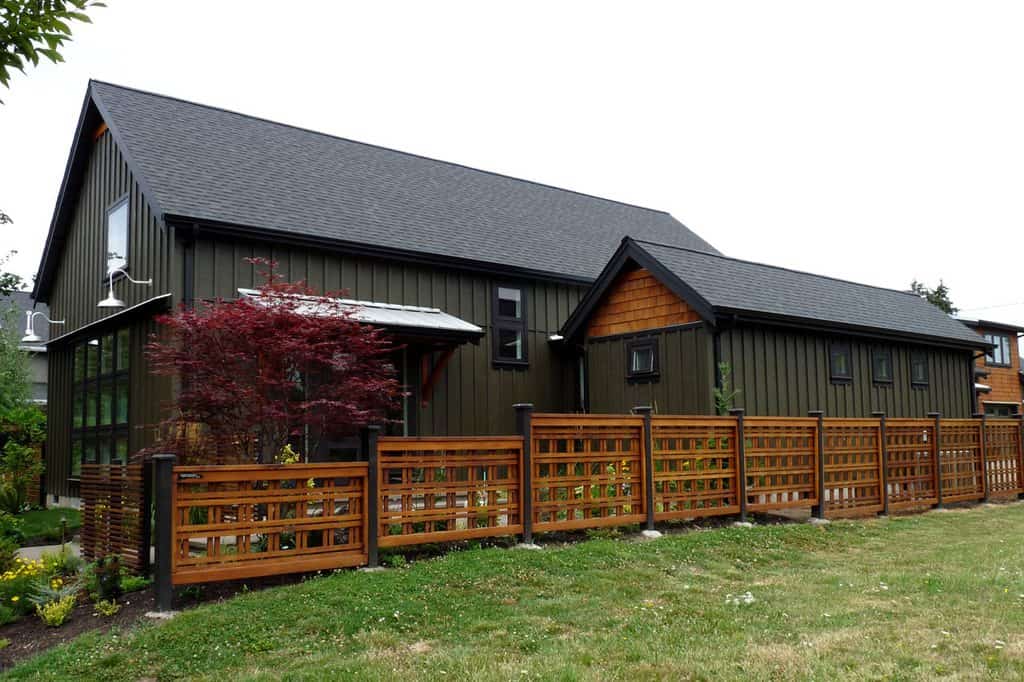 black barndominium with wooden fence
