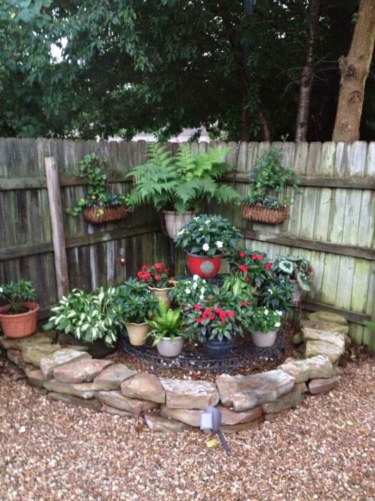 an image showing a corner of a garden with rock boundary and flower pots inside