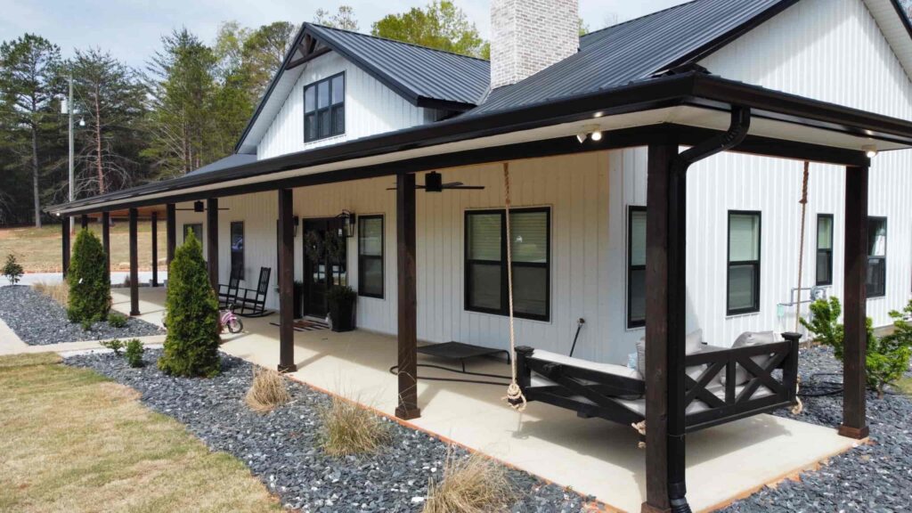a white barndominium house with black accent on door, windows, porch columns