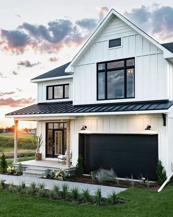 white barndominium with black entry door and garage door