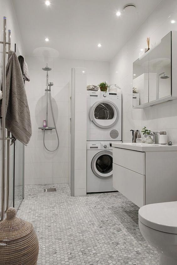 an image of a white minimalist bathroom with shower, toilet, washer, and dryer