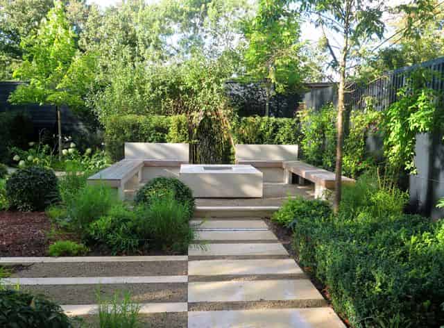 an image of a white seating area in the middle of a garden filled with plants and flowers